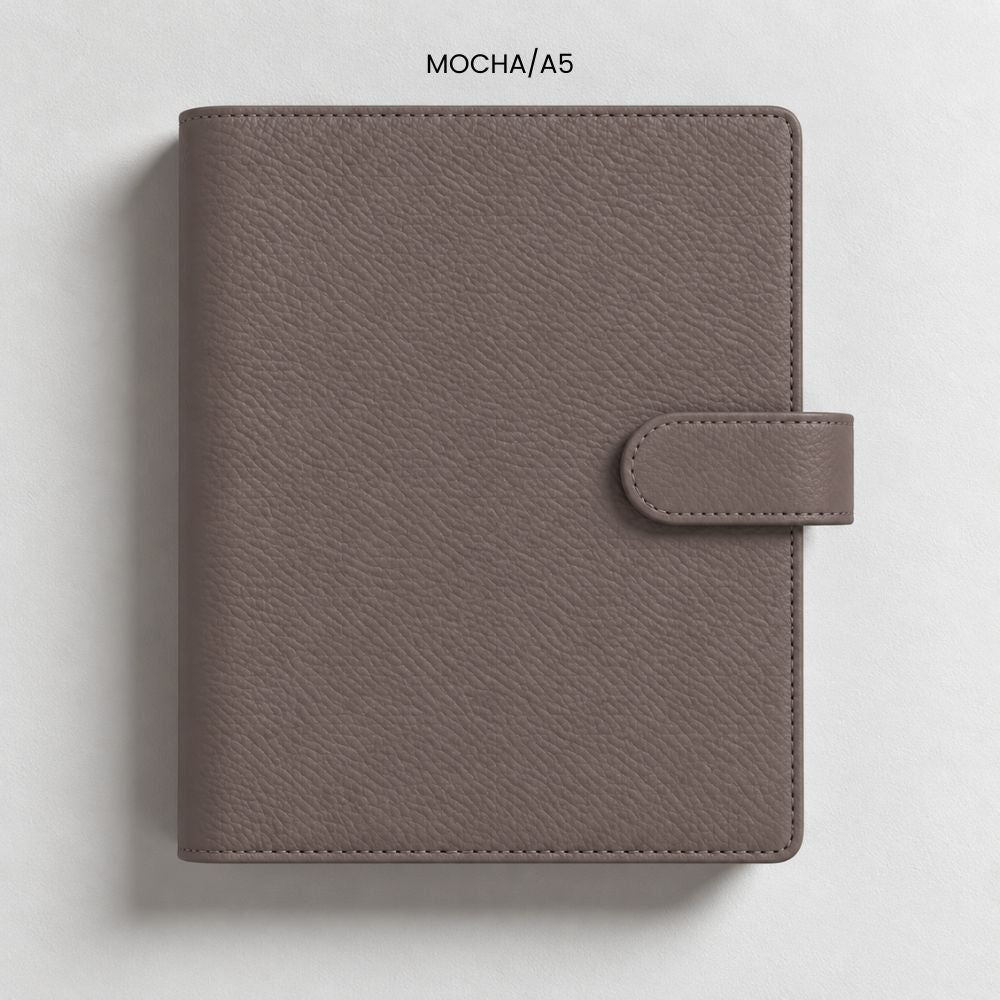 An A5 textured agenda binder cover in a muted mocha-brown colour, featuring a snap-button closure tab on the right side, photographed flat against a light gray background.