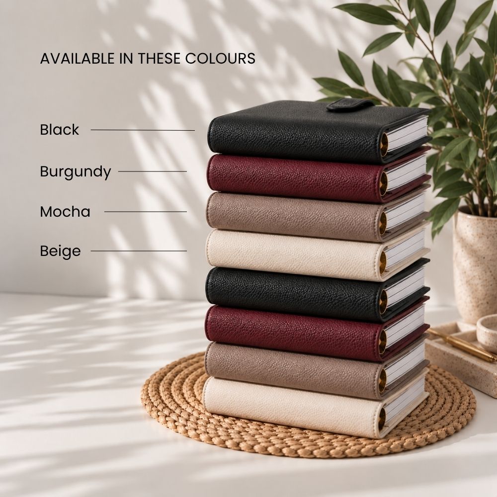 A stack of six textured agenda covers in black, mocha brown and beige, displayed on a woven mat with text labels indicating the available colors.