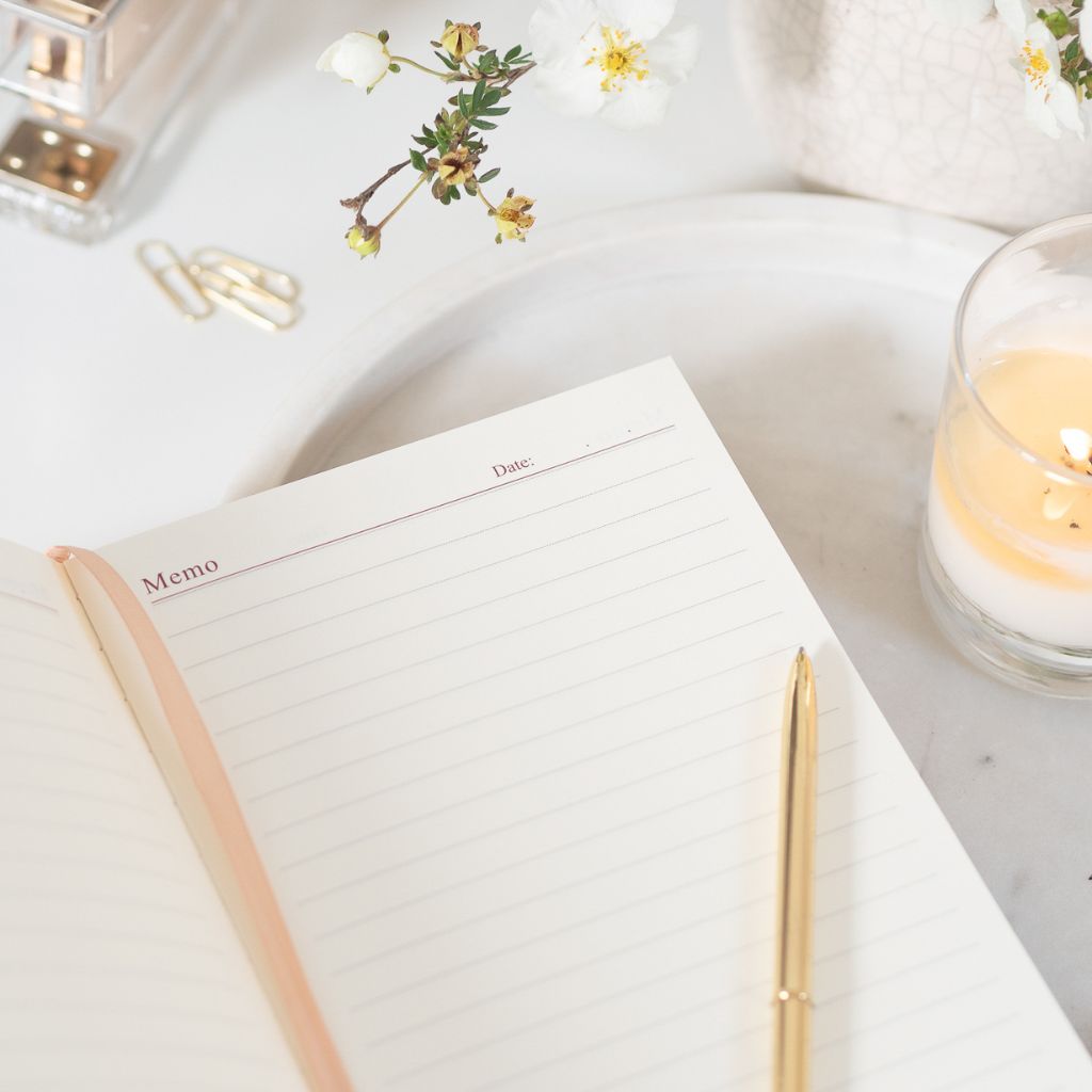 a5 lined neutral notebook open with pen and candle